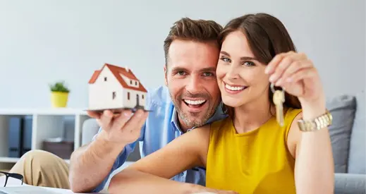 Happy Couple Holding Keys to New Home and House Miniature